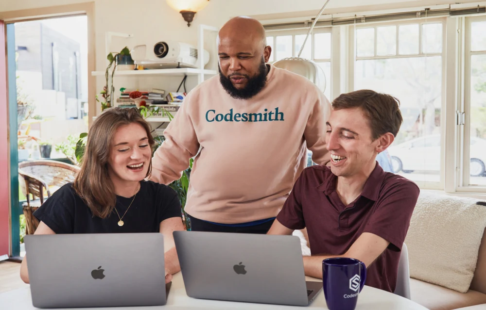 Codesmith learners collaborating around laptops
